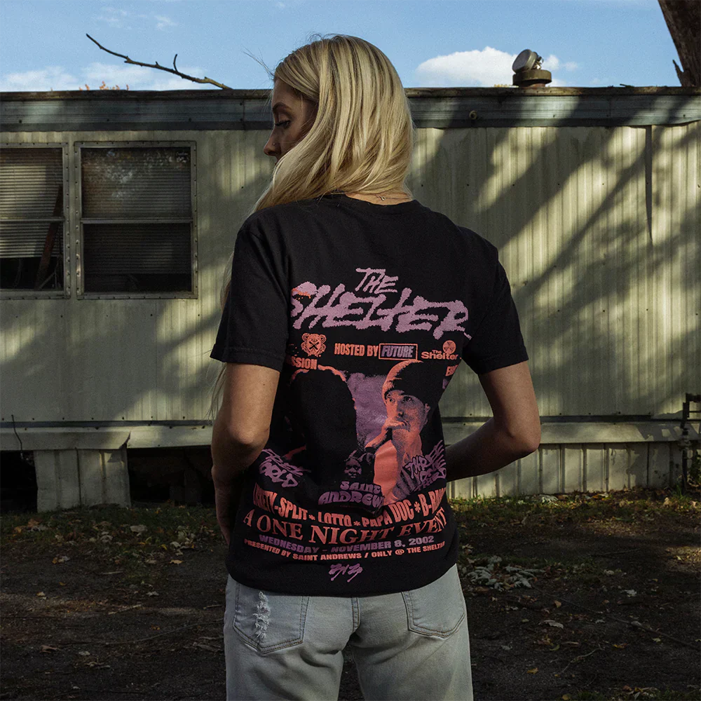 Back of The Shelter Event Black T-Shirt worn by a woman, highlighting the detailed event poster print with Eminem's figure and venue details - Eminem Concert Series.