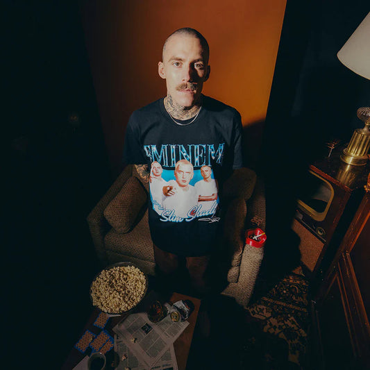 Model in a vintage setting wearing Eminem SSLP25 Bootleg T-shirt, featuring a collage of Eminem's Slim Shady personas with icy blue accents.